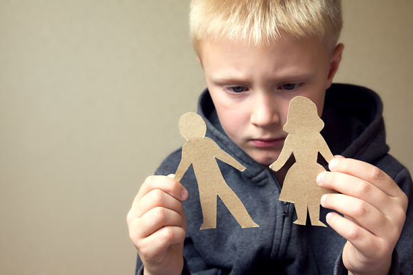 Child holding cutouts of parents trying to decide between the two