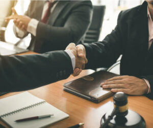a legal team speaking with their client and shaking their hand.