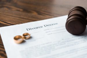 divorce papers with two wedding rings and judge's gavel on top