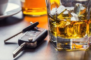 DWI defense lawyer in Galveston. Car keys and glass of alcohol on table in pub or restaurant.